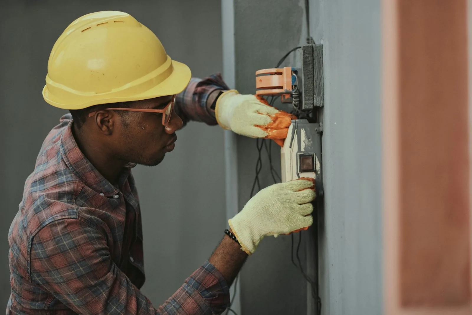 Electrician in a hard hat wiring a box on a wall