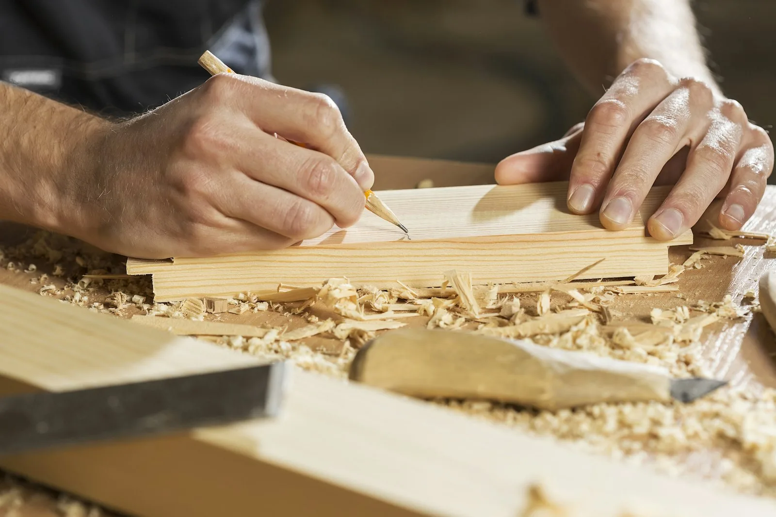 Carpenter marking a board with a pencil