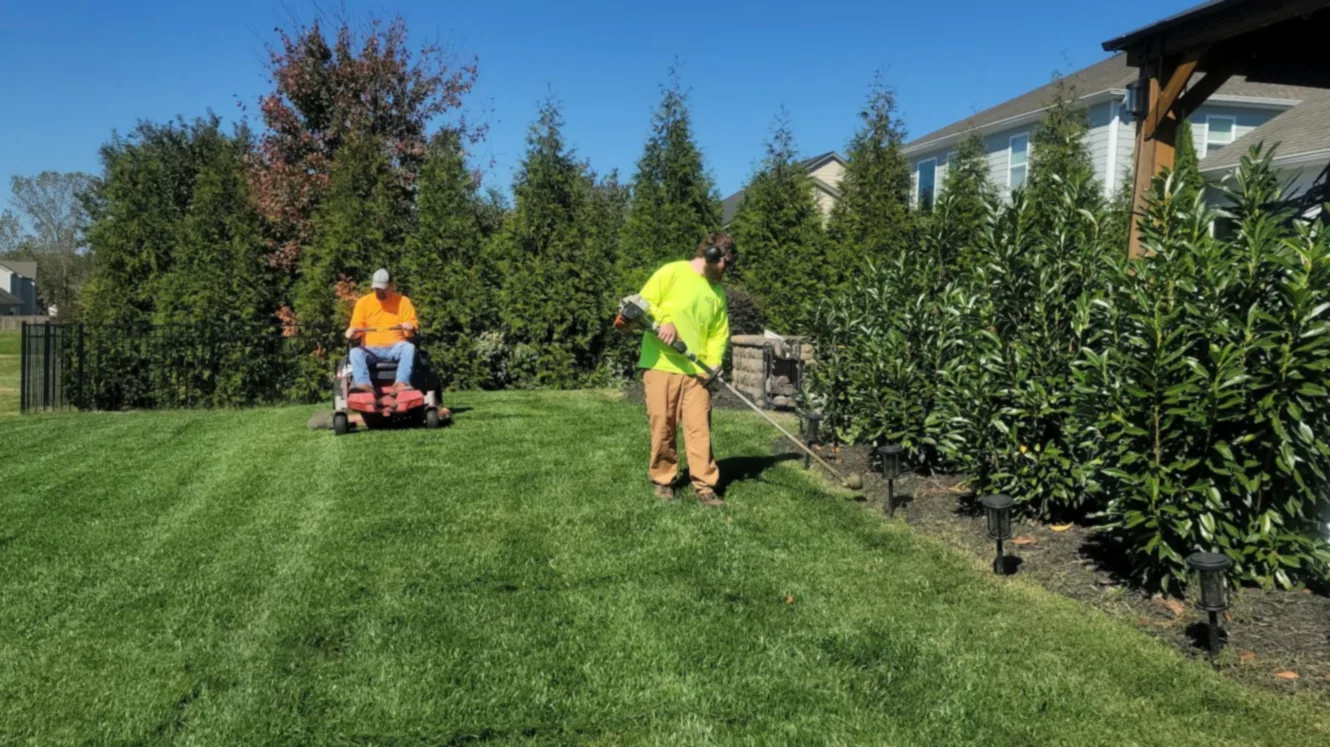 Lawn crew mowing and edging a striped lawn