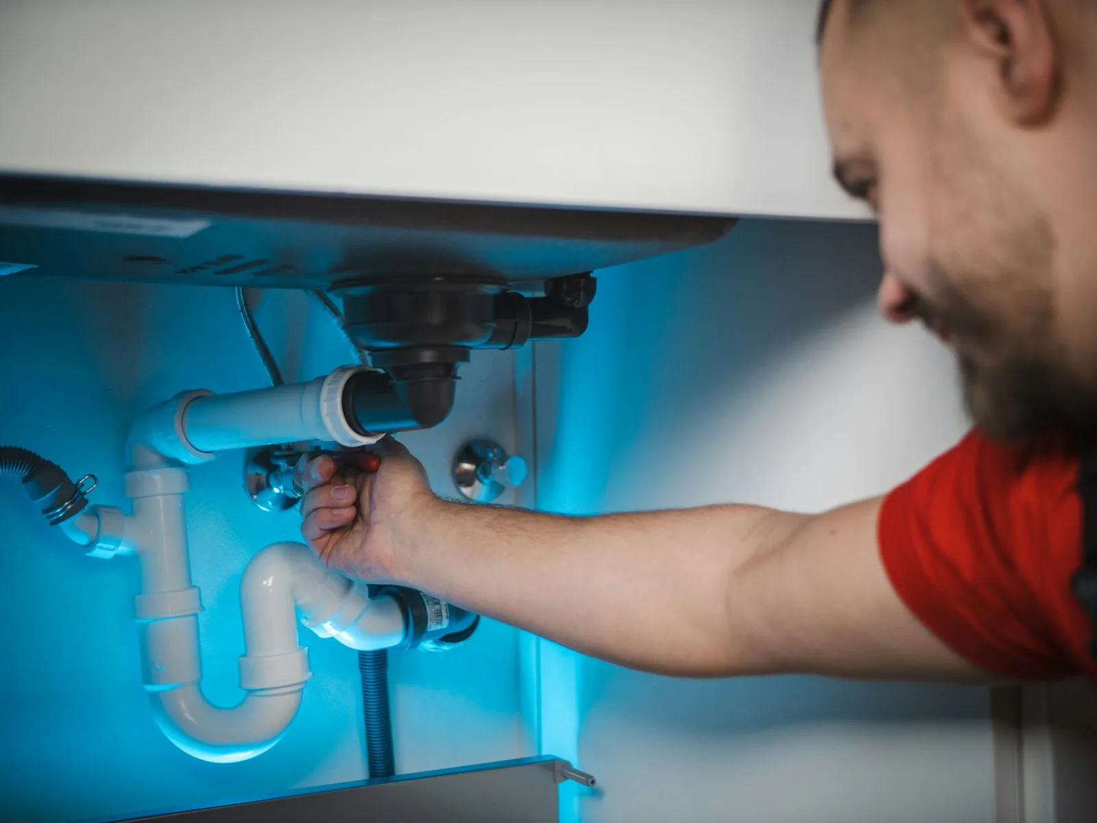 Plumber fitting a drain pipe under a sink